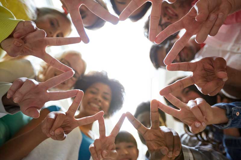 Teen body image group - teens in a circle showing peace signs with their hands